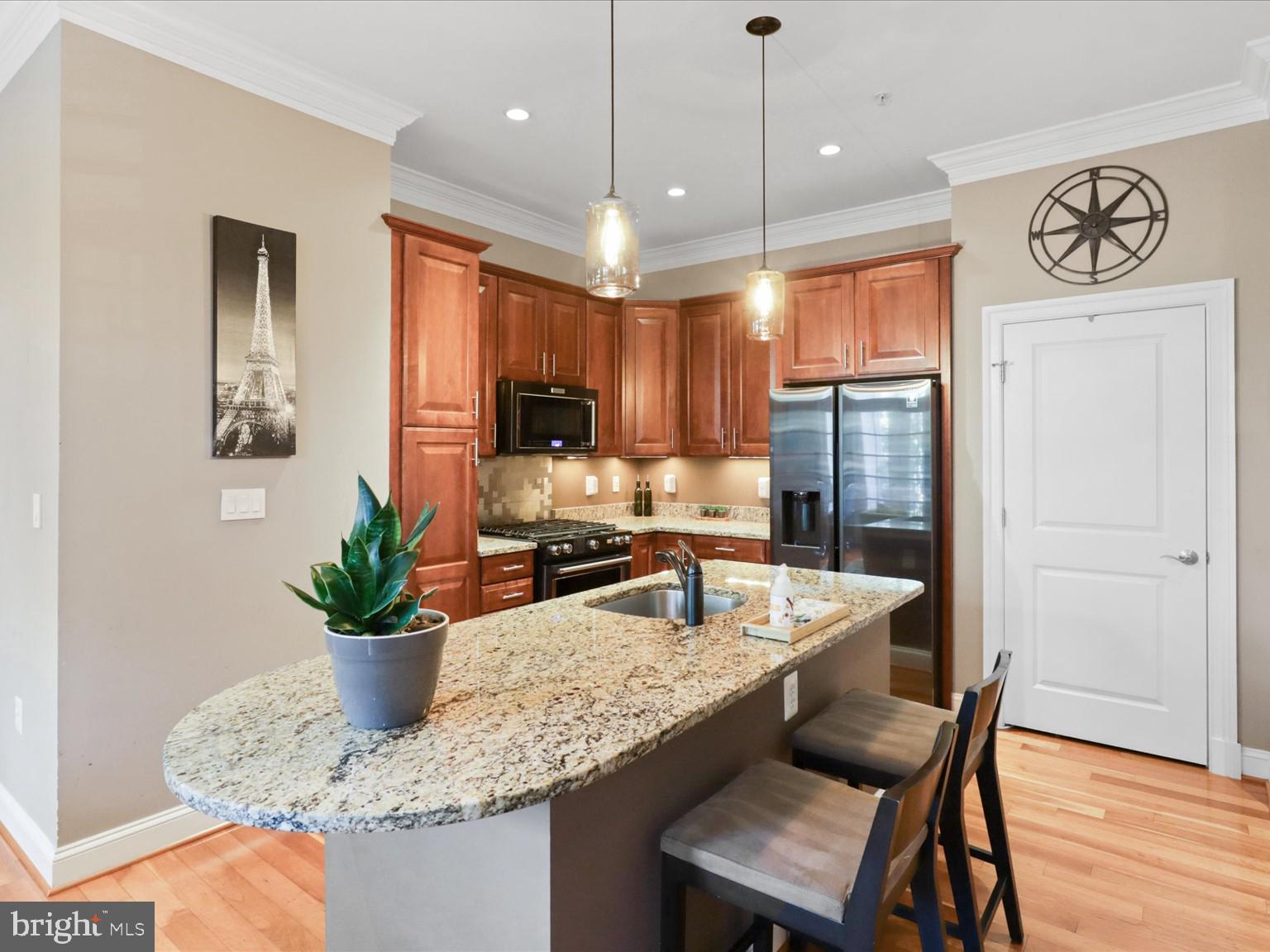 1023 North Royal Street, Unit 214 Alexandria, VA 22314 - Photo 4 of 38 a kitchen with granite countertop kitchen island stainless steel appliances a dining table chairs sink and wooden floor