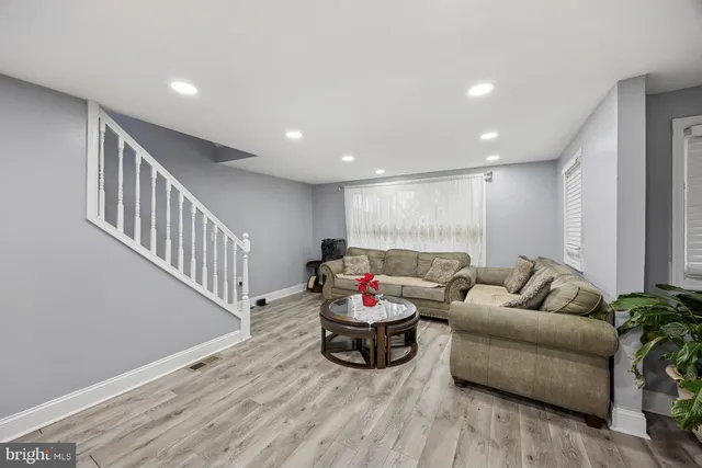 a living room with furniture stairs and a wooden floor