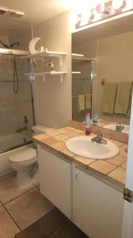 a bathroom with a granite countertop sink a toilet and shower