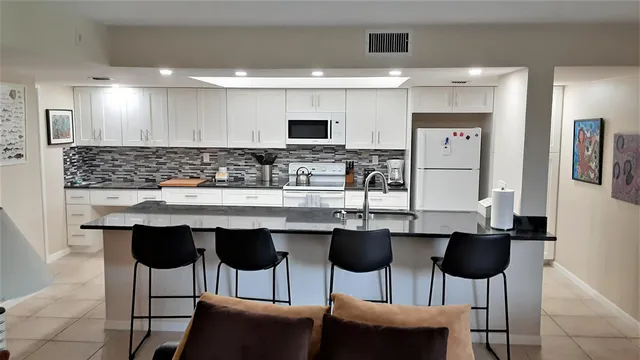 a kitchen with a dining table chairs sink and white cabinets