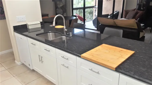 a kitchen with granite countertop a sink and a white cabinets