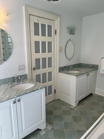 a bathroom with a granite countertop double vanity sink and a mirror