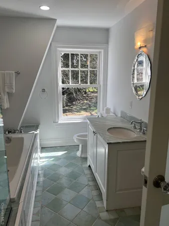 a bathroom with a granite countertop sink mirror vanity and toilet