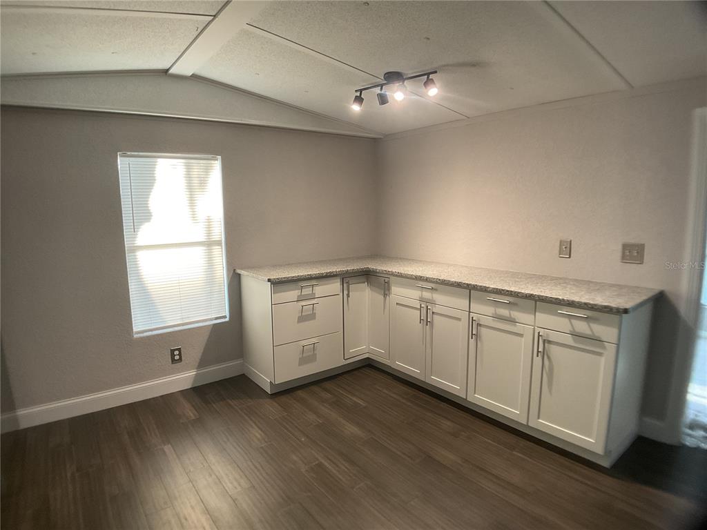 5038 Northeast Sandy Road Arcadia, FL 34266 - Photo 6 of 42 a kitchen with wooden floors white cabinets and window
