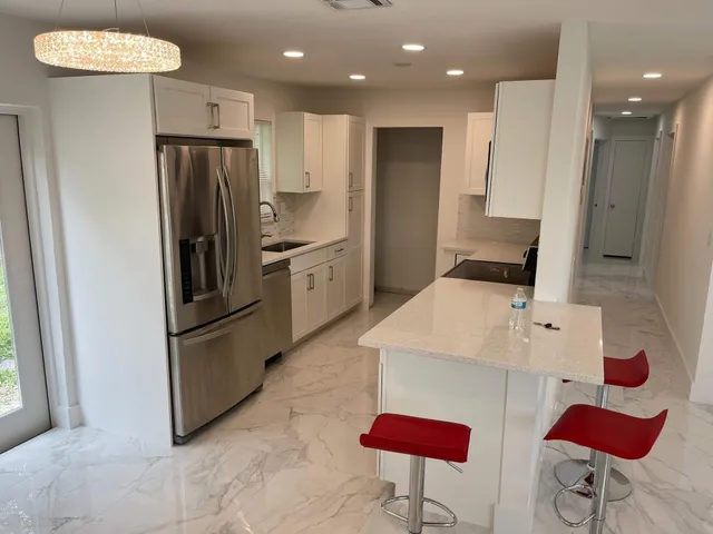 a kitchen with stainless steel appliances kitchen island granite countertop a refrigerator and a sink