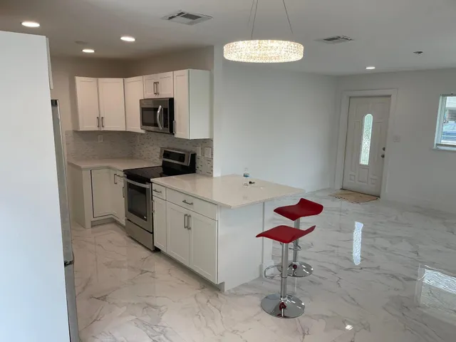 a kitchen with stainless steel appliances granite countertop a sink a stove a microwave a refrigerator and cabinets