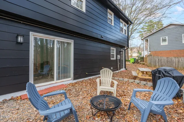 a backyard of a house with fire pit table and chairs
