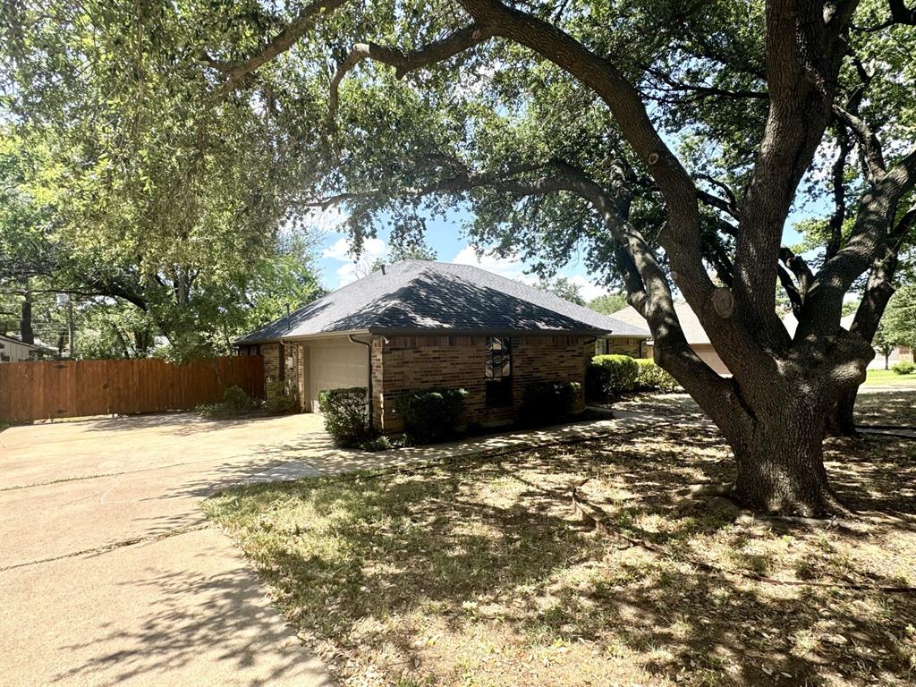 113 Northeast Timber Ridge Drive Burleson, TX 76028 - Photo 2 of 36 Side-Entry 2-CAR Garage with swing driveway, brick exterior, dark shingle roof, and mature front yard trees. Newer WOOD Fence too!