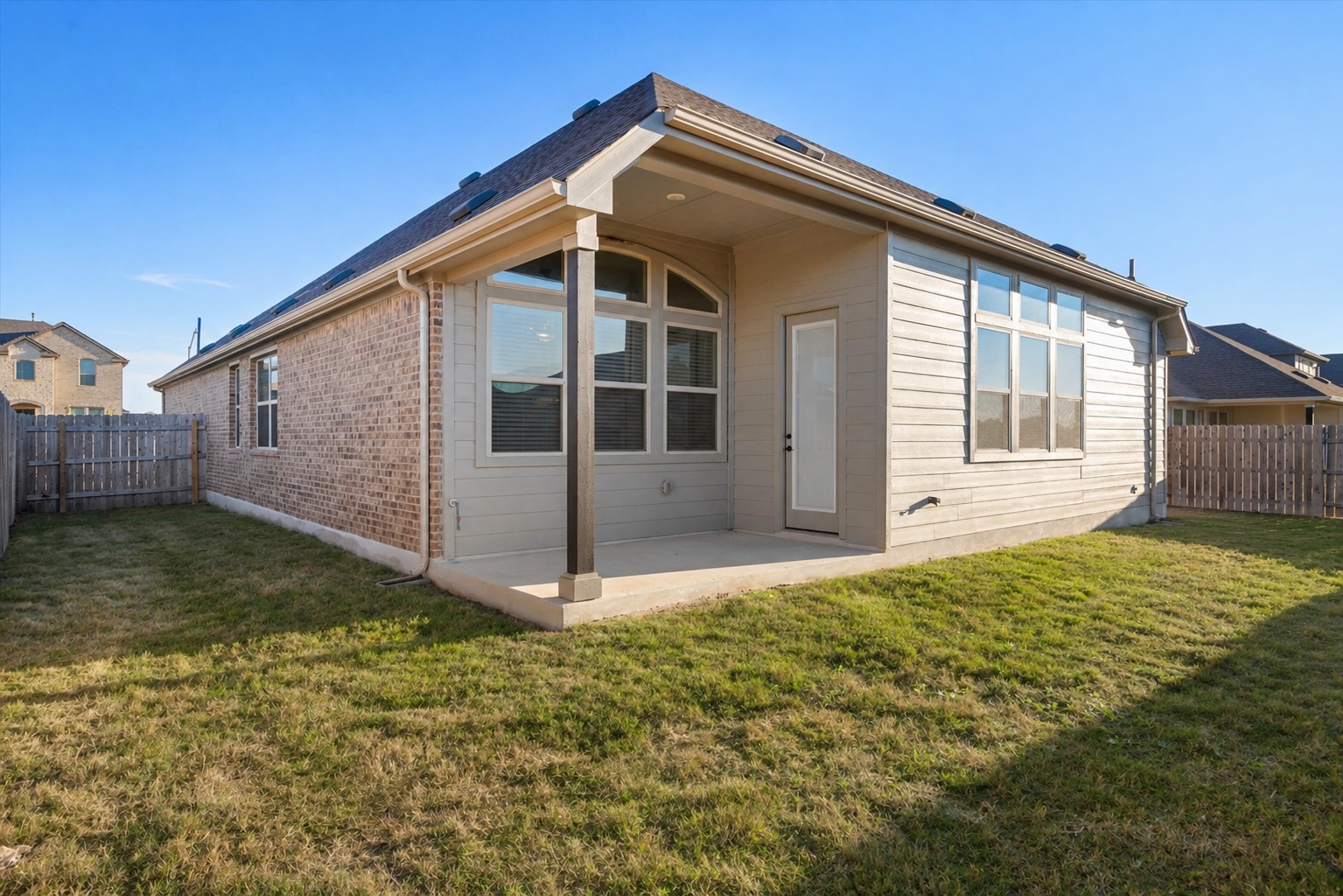 209 Rainier Drive Kyle, TX 78640 - Photo 23 of 24 Expansive backyard featuring a covered patio, brick and siding exterior, large windows, and a wood privacy fence