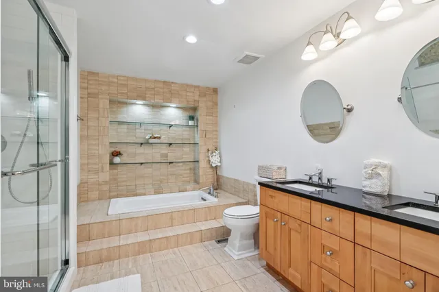 a bathroom with a double vanity sink mirror and bathtub
