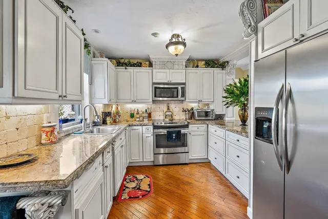 a kitchen with stainless steel appliances granite countertop a sink a stove and a refrigerator