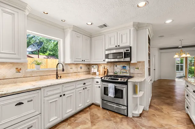 a kitchen with stainless steel appliances granite countertop a stove a sink and a microwave