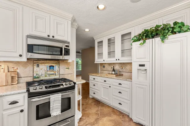 a kitchen with stainless steel appliances white cabinets and a stove top oven
