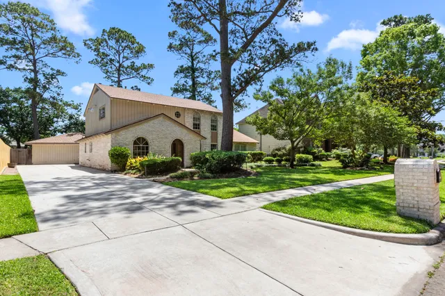 a view of a house with a yard and large tree