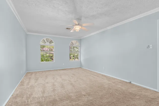 an empty room with windows and ceiling fan view
