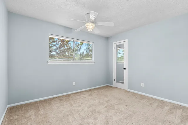 an empty room with windows and fan