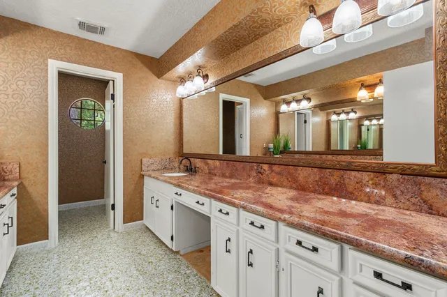 a bathroom with a granite countertop sink and a mirror