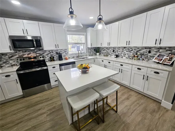 a kitchen with stainless steel appliances granite countertop a stove a sink dishwasher a microwave oven with cabinets and wooden floor
