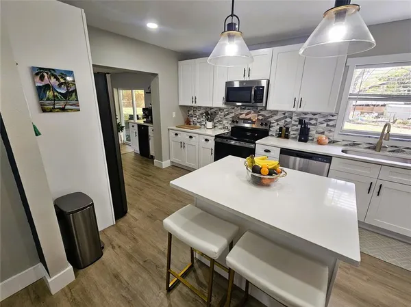 a kitchen with a sink a stove a microwave a dining table and chairs