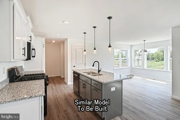 a kitchen with stainless steel appliances granite countertop a sink a stove and a wooden floor