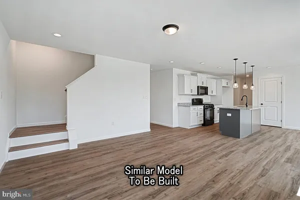 a large white kitchen with a refrigerator a stove top oven and wooden floor