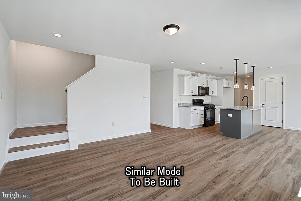 Meriwether Plan At The Seasons Dover, PA 17315 - Photo 8 of 30 a large white kitchen with a refrigerator a stove top oven and wooden floor