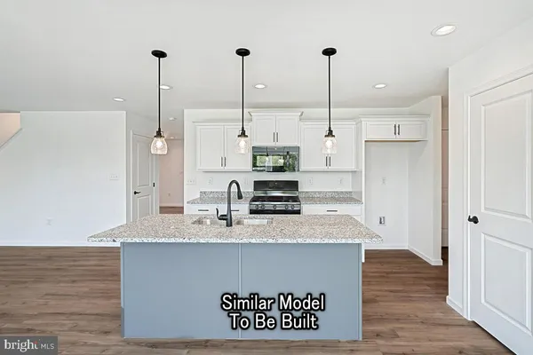 a view of a kitchen with kitchen island stainless steel appliances wooden floor