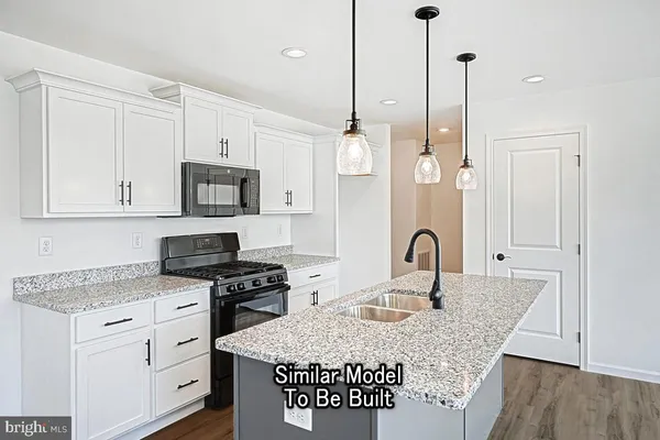 a kitchen with granite countertop a stove a sink and a refrigerator