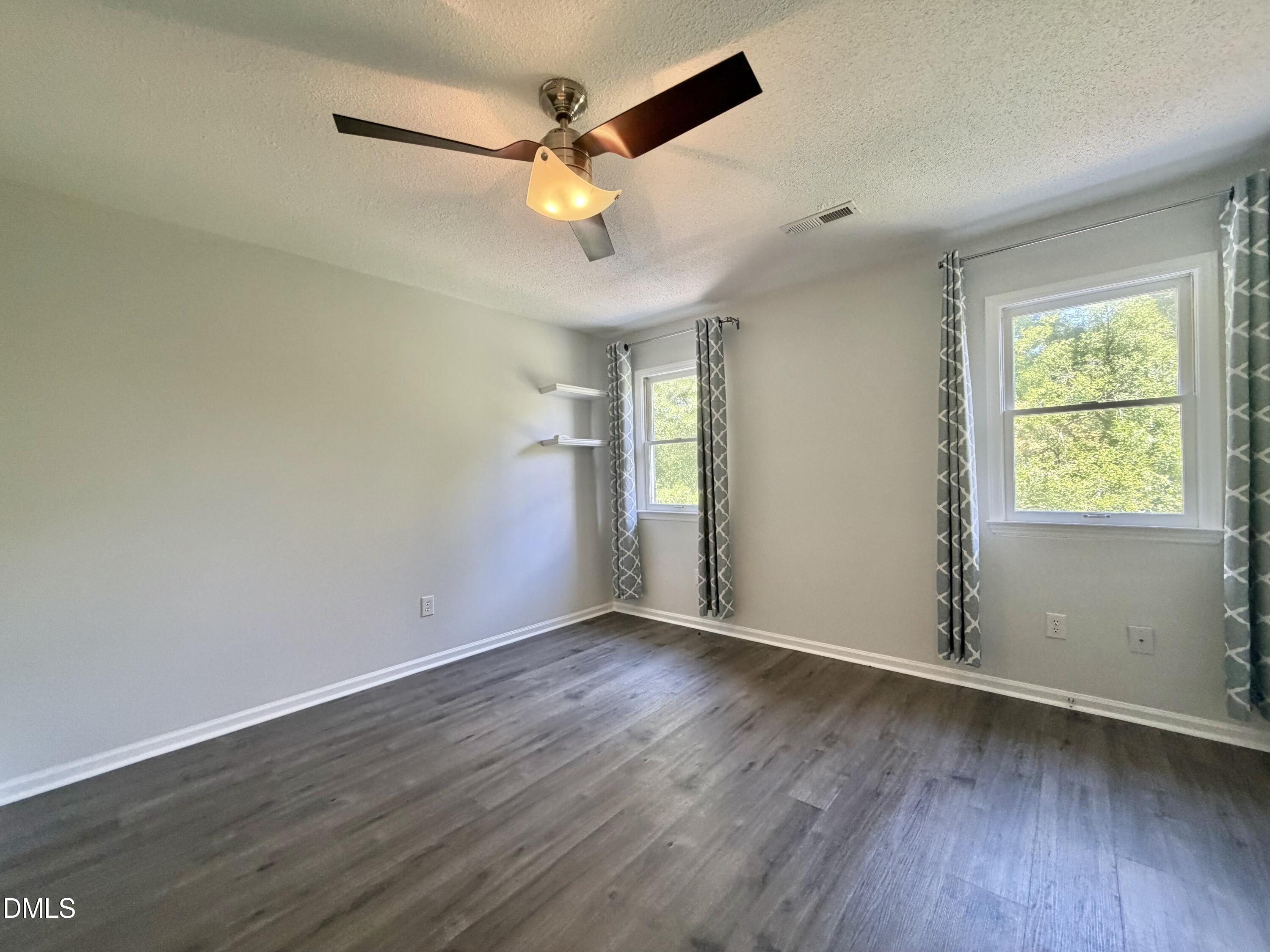 333 Jones Franklin Road, Unit B Raleigh, NC 27606 - Photo 6 of 9 an empty room with wooden floor chandelier fan and windows