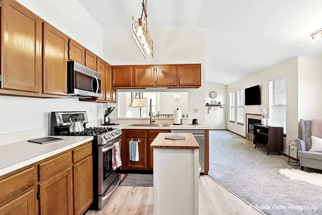 a kitchen with stainless steel appliances granite countertop a stove top oven a sink dishwasher a refrigerator and cabinets with wooden floor