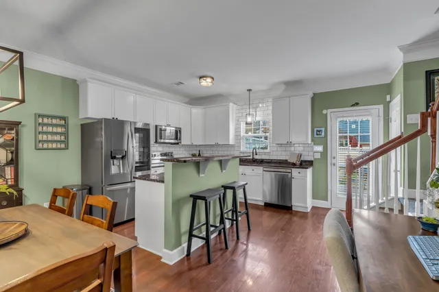 a kitchen with stainless steel appliances granite countertop a refrigerator a stove top oven a sink dishwasher and white cabinets with wooden floor