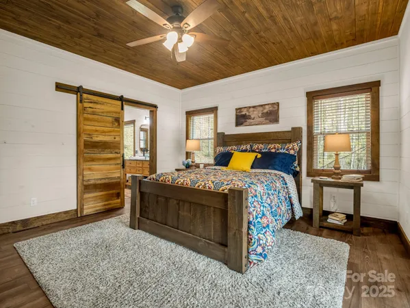 a bedroom with a bed and dresser with wooden floor