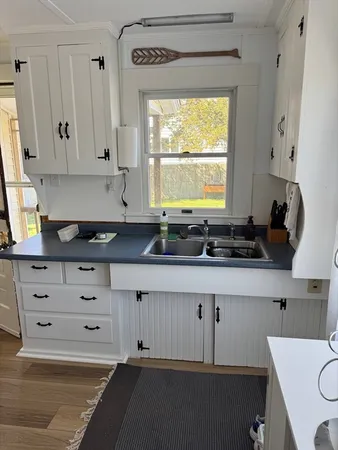 a kitchen with granite countertop white cabinets white appliances and a window