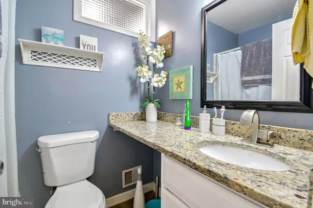 a bathroom with a granite countertop toilet sink and mirror