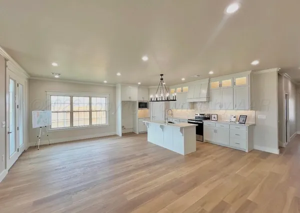 a large kitchen with stainless steel appliances kitchen island a large counter top and a wooden floors