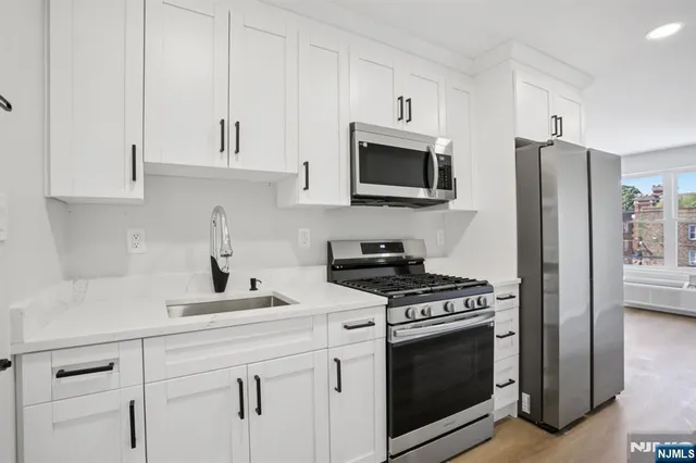 a kitchen with white cabinets and stainless steel appliances