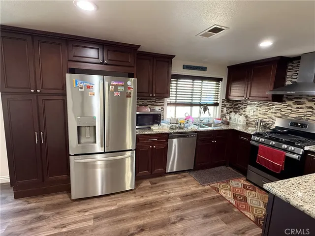 a kitchen with stainless steel appliances granite countertop a refrigerator and a stove top oven