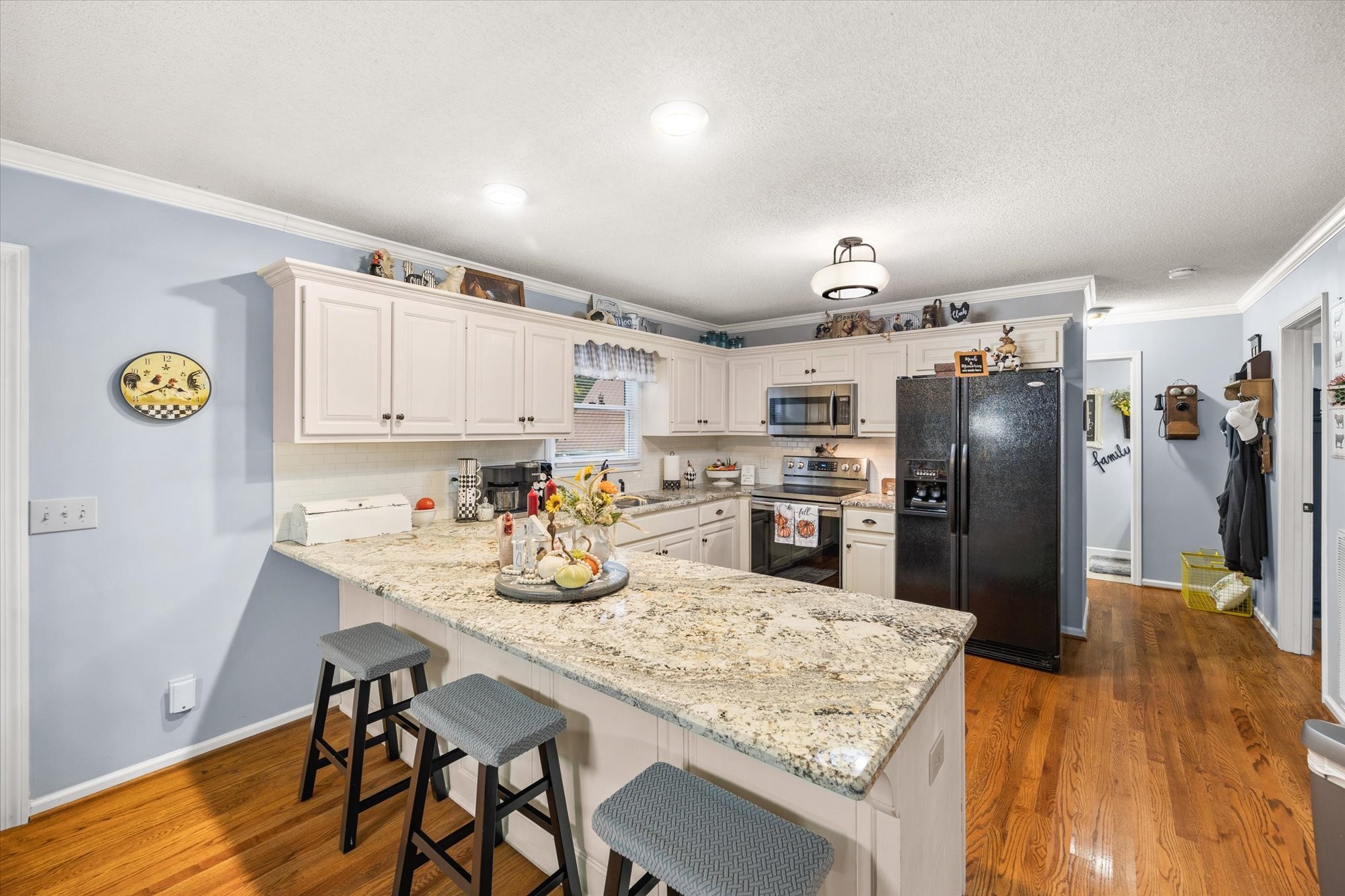 7214 Sarah Thomas Road Silver Point, TN 38582 - Photo 6 of 52 a kitchen with granite countertop a refrigerator a stove a sink dishwasher and white cabinets with wooden floor