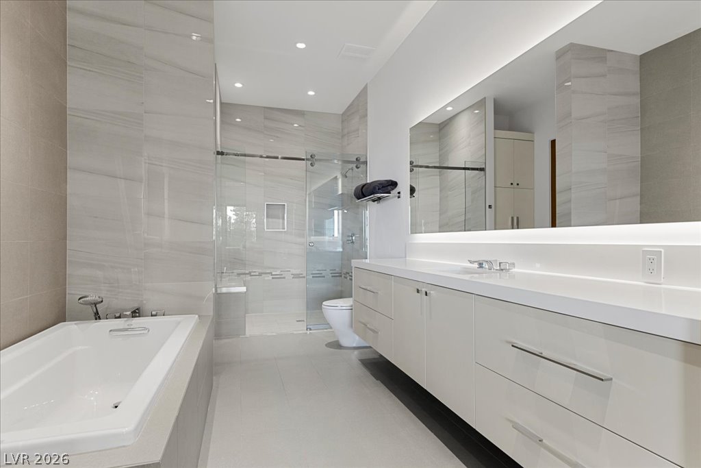 657 Ridgestone Rim Court Henderson, NV 89012 - Photo 67 of 97 Clean lines and stone surfaces define this modern bathroom with a glass-enclosed shower.
