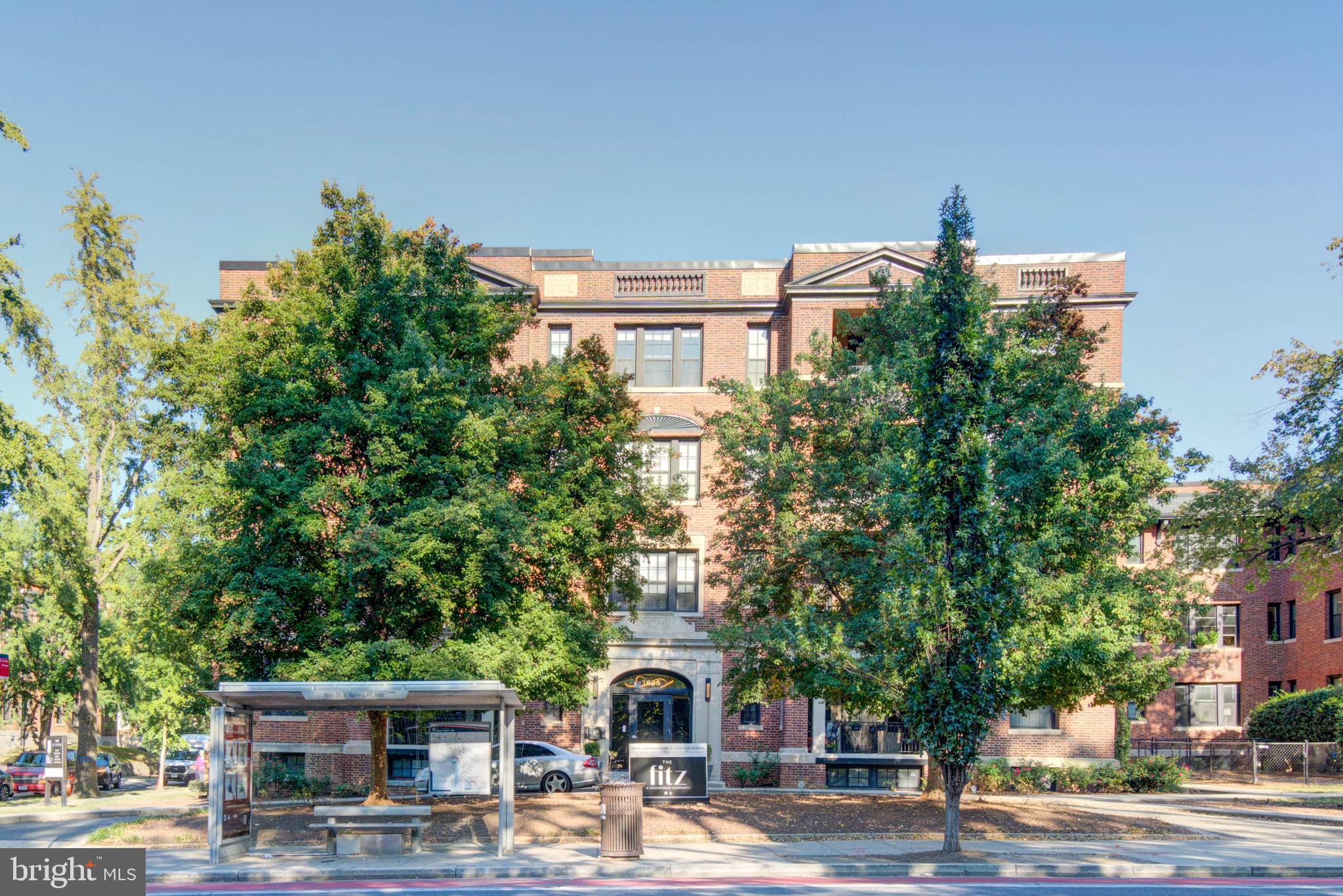 a front view of a building with lots of trees and plants