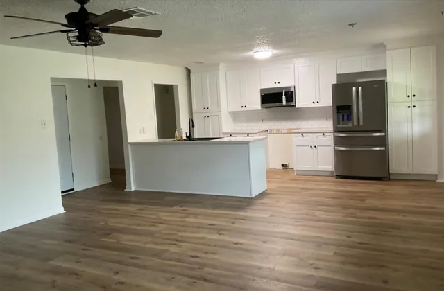 a view of kitchen with stainless steel appliances granite countertop a stove top oven a refrigerator a sink with wooden floors