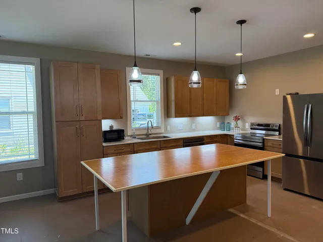 a kitchen with kitchen island a large counter top space appliances and windows