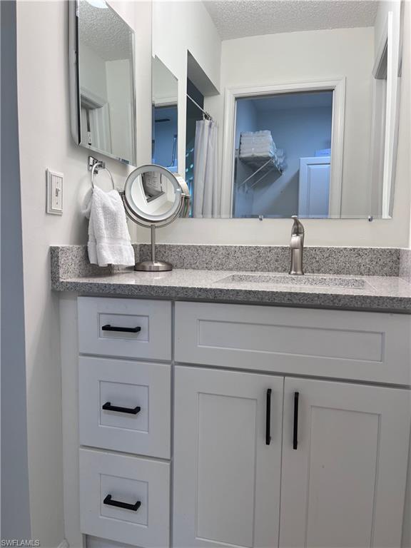 3685 Amberly Circle, Unit D305 Naples, FL 34112 - Photo 11 of 42 a bathroom with a granite countertop toilet sink and mirror