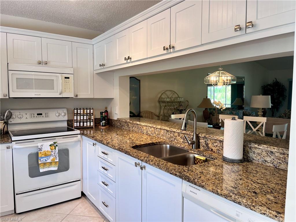 3685 Amberly Circle, Unit D305 Naples, FL 34112 - Photo 3 of 42 a kitchen with stainless steel appliances granite countertop a sink white cabinets and a granite counter tops