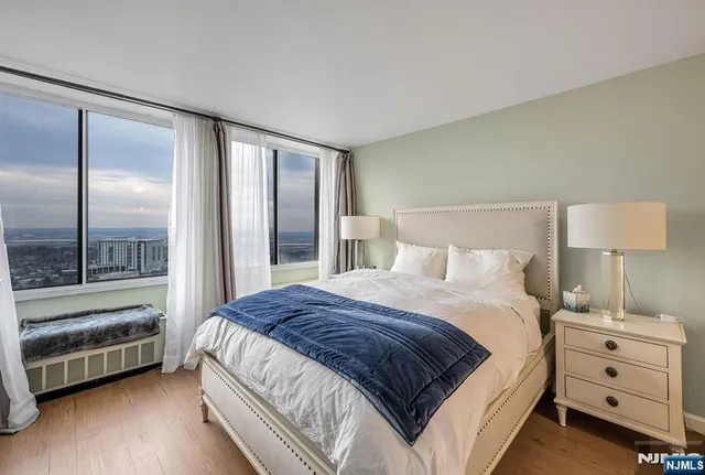 a spacious bedroom with a bed and a lamp on a dresser