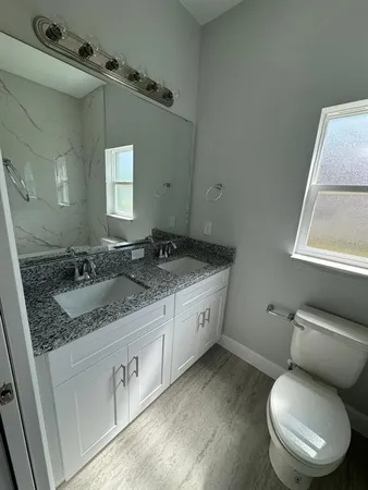 a bathroom with a granite countertop toilet sink and mirror