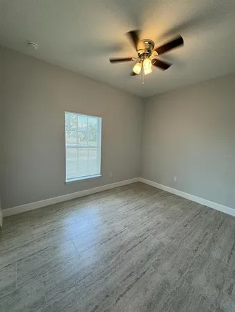 an empty room with wooden floor fan and windows