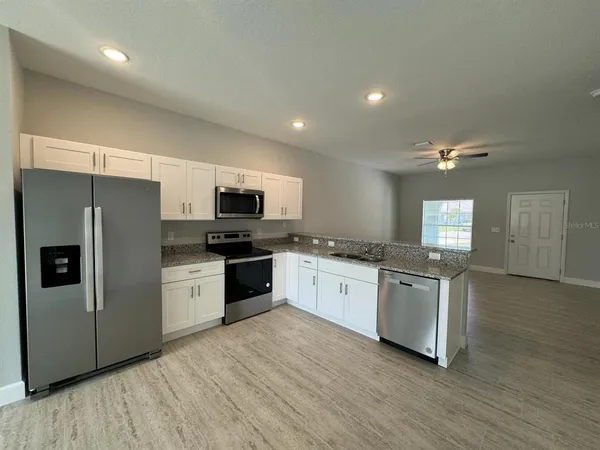a large kitchen with granite countertop a refrigerator stove top oven and sink