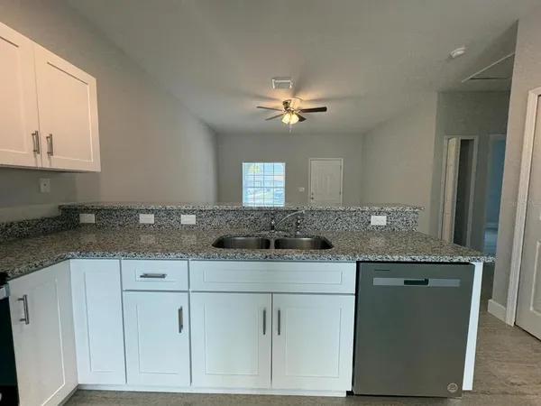 a kitchen with granite countertop a sink stainless steel appliances and cabinets