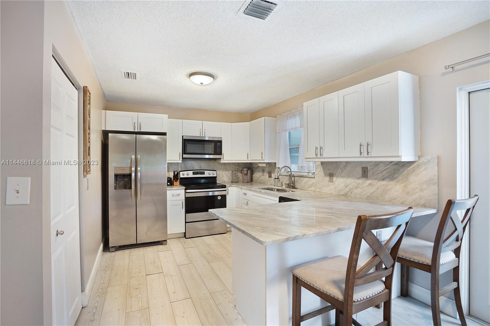 1330 Sesame Street Opa-Locka, FL 33054 - Photo 10 of 27 a kitchen with kitchen island a refrigerator stove microwave and cabinets